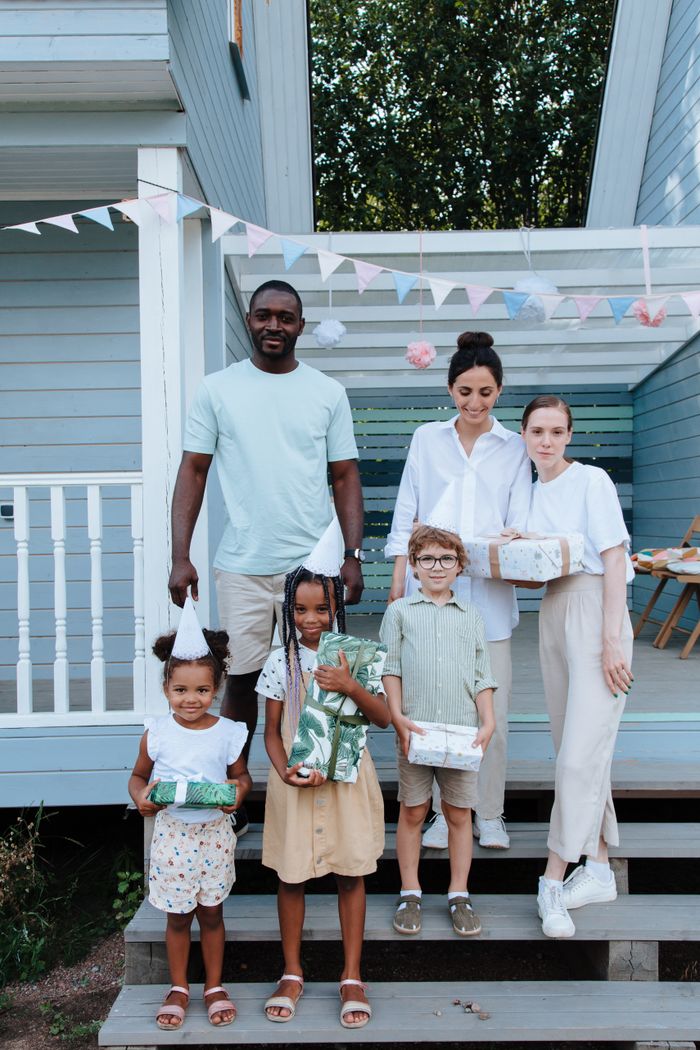 Services A diverse family celebrating a birthday outdoors, exchanging gifts and enjoying family time.