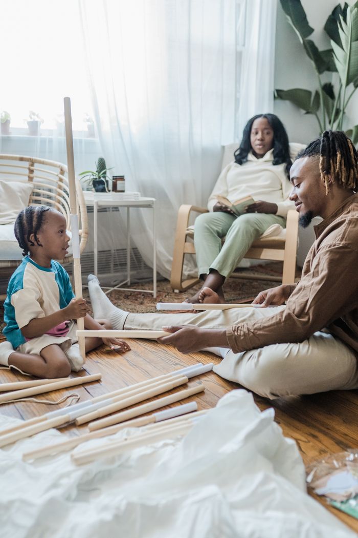 About Father and child building structure at home with mother watching.