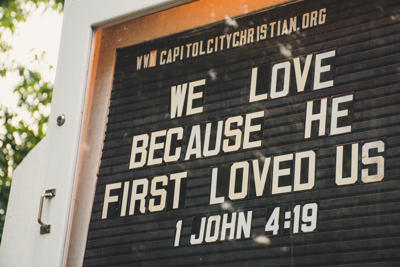 Crafting Captivating Headlines: Your awesome post title goes here Church sign displaying biblical verse about love from 1 John 4:19 in outdoor setting.