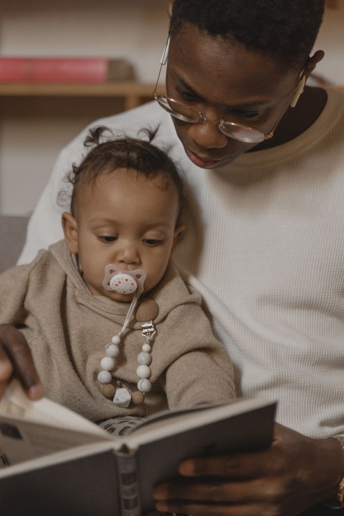 About A father lovingly reads a story to his baby daughter, fostering a bond and early learning.